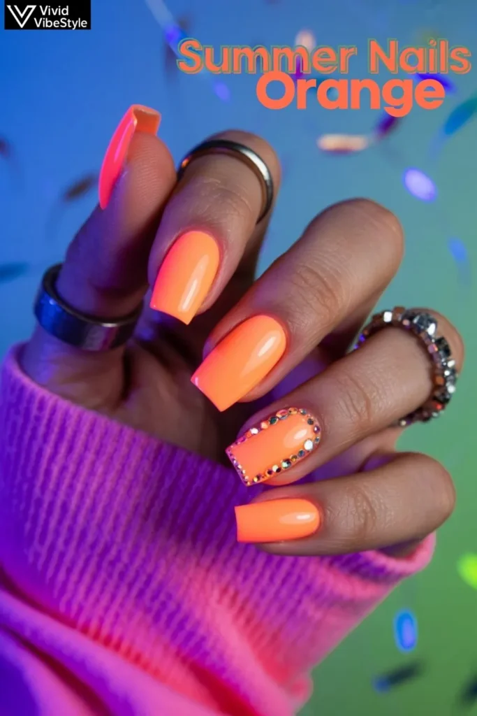 Neon orange nails with glow-in-the-dark effects and rhinestone accents styled for festival season