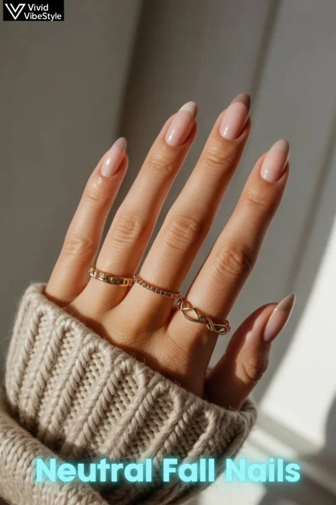 Hands with blush neutral fall nails styled with gold rings and a chunky knit sweater