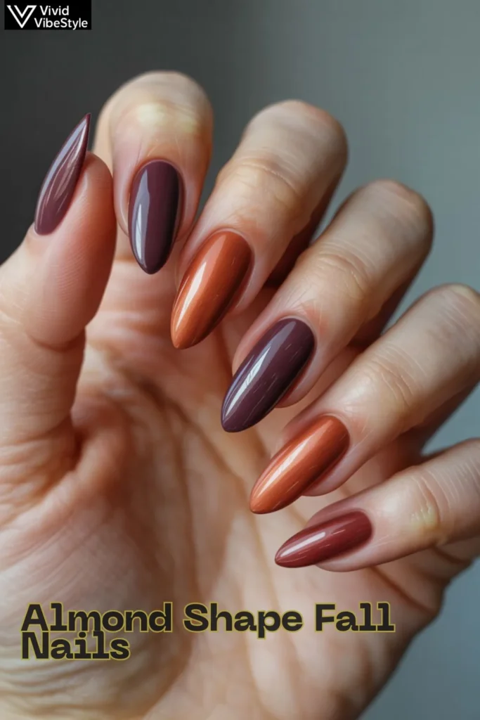 Close-up of almond-shaped nails in fall colors like rust and plum, showing elegant and flattering nail shape.