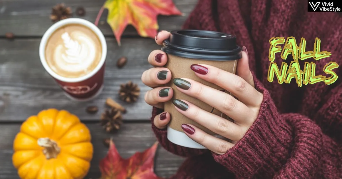 Close-up of fall nails in burgundy and green holding a pumpkin spice latte, surrounded by autumn leaves and cozy fall fashion accessories