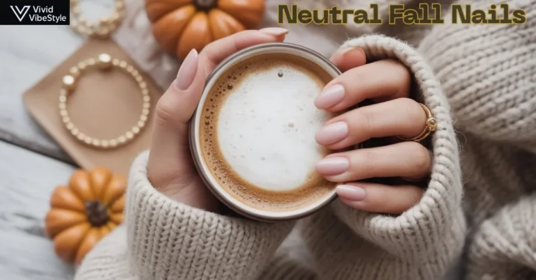 Woman holding a coffee cup with neutral fall nails in beige tones, styled with a cozy knit sweater and gold rings