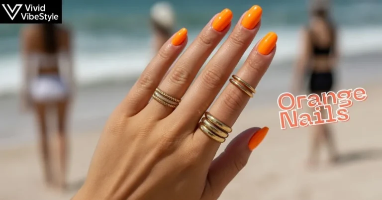 Glossy neon orange nails with gold rings in natural sunlight showcasing the 2025 vibrant nail trend